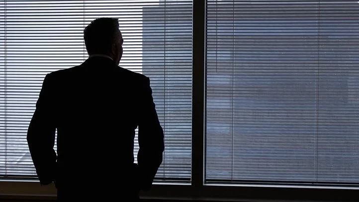 窓の外を見つめるビジネスマンの男性の後ろ姿。 ネガティブな印象のイメージ。