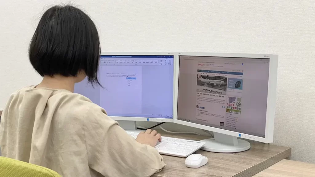 ディスプレイの前に座った女性の画像